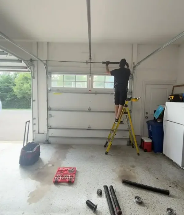 Technician replacing garage door torsion springs